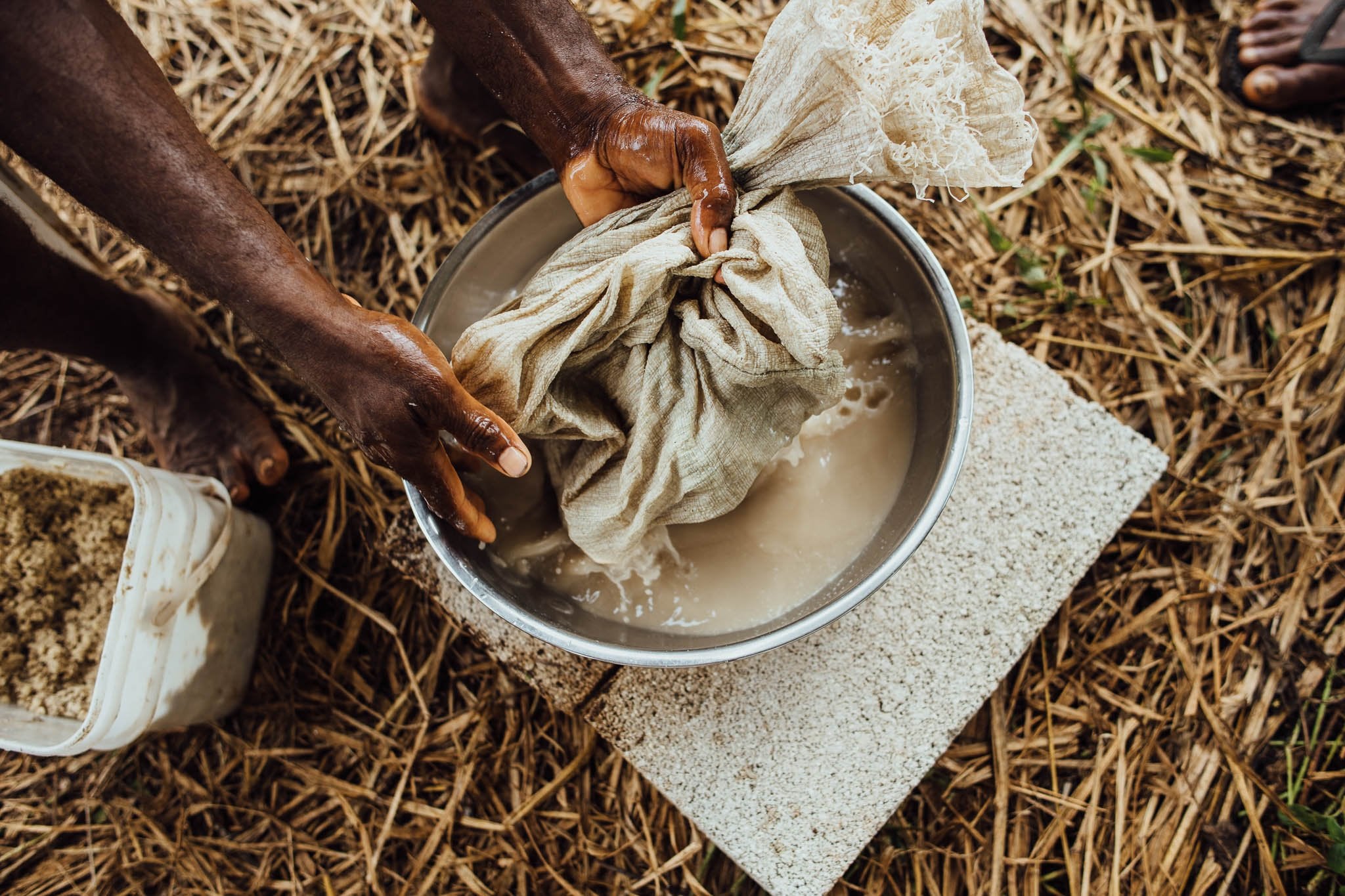 Fresh kava being prepared traditionally with a cotton strainer bag and stainless steel bowl in a Forney Enterprises facility in Vanuatu