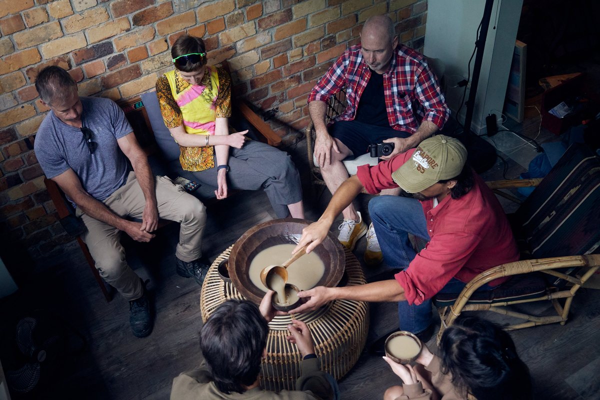 Friends sharing kava around a traditional kava bowl at Four Shells Kava Lounge in Auckland